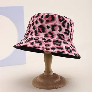 Pink leopard print reversible bucket hat shown on a wooden stand in a clean studio setting