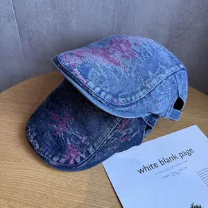 Détail de casquettes plates en jean délavé bleu avec motifs roses vieillis