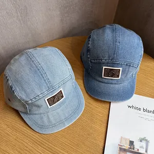Fashionable denim baseball caps with metal ring patches on a rustic wooden table