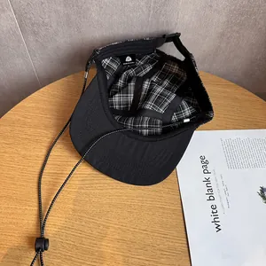 Dettaglio cappello nero da outdoor con fodera a scacchi e cordino regolabile