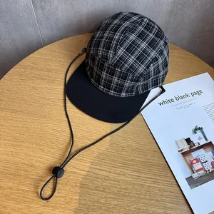 Dettaglio cappello 5-panel a scacchi con tesa piatta nera e cordino regolabile