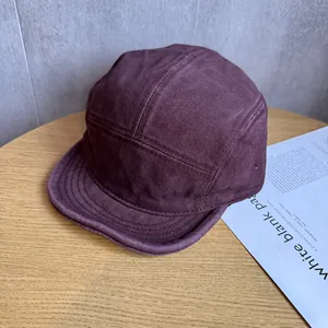 Λεπτομέρεια μπορντό καπέλου camper 5-panel σε ξύλινο τραπέζι με αισθητικό περιοδικό