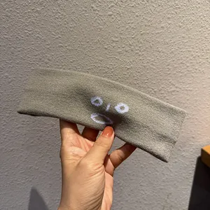 Gros plan d'un bandeau en tricot gris avec un visage surpris brodé de fil blanc