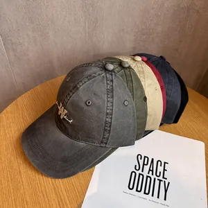 Five assorted vintage washed cotton baseball caps with embroidered letters on a wooden table
