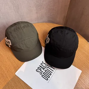 Casquettes de camp 5-panel noir et vert armée avec logo TP blanc sur une table en bois
