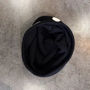Primo piano di un berretto nero a maglia con pois bianchi e trama a costine