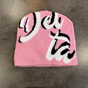Dettaglio del berretto in maglia rosa con texture jacquard a lettere gotiche bianche e nere