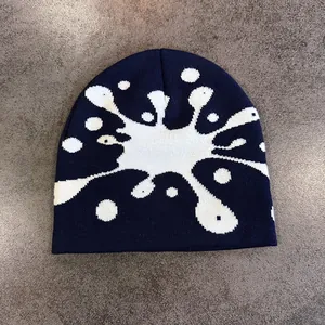 Dettaglio del berretto in maglia blu intenso con motivo fluido bianco astratto e pois