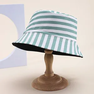 Reversible green and white striped cotton bucket hat displayed on a wooden stand