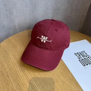 Close-up of white letter embroidery on burgundy cotton twill baseball cap with curved brim