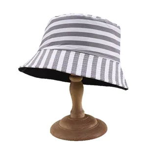 Grey and white striped reversible bucket hat for sun protection on a wooden display stand