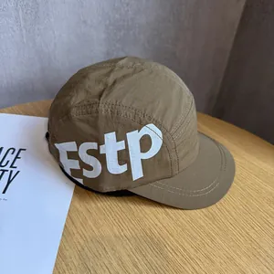 Détail d'une casquette camp en nylon kaki foncé avec grand imprimé blanc ESTP sur bois