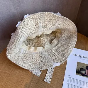 Détail macro du chapeau de paille beige avec des cœurs en dentelle et longs rubans