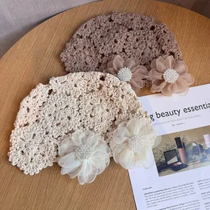 Détail de chapeaux en crochet avec fleurs en résille et perles sur fond de bois