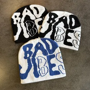 Three Y2K style knit beanies with Bad Vibes jacquard text in black, white, and blue colors