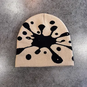 Vista dettagliata del berretto in maglia beige con motivo jacquard astratto nero e trama