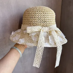 Détail d'un chapeau de paille tissé avec fleurs en dentelle blanche et ruban élégant