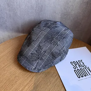 Détail du béret à carreaux gris présentant des motifs de feuilles d'érable sur tissu texturé