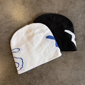 Detail of black and white knitted beanies featuring abstract street style graphics