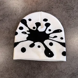 Dettaglio del berretto in maglia bianco con schizzi di inchiostro nero e trama morbida