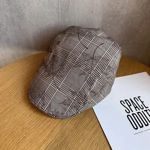 Détail de béret à carreaux marron avec motifs feuilles d'érable sur surface en bois