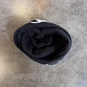 Close-up of dual-tone knit beanie featuring white letter patterns and thick texture