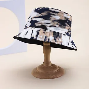 Detailed view of tie-dye bucket hat with abstract ink pattern on vintage wooden stand