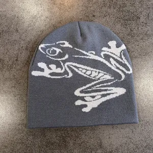 Dettaglio macro del berretto grigio scuro con motivo jacquard a rana in maglia bianca