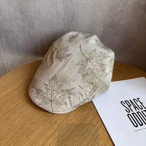 Gros plan sur une casquette gavroche à carreaux marron clair et motif feuille d'érable