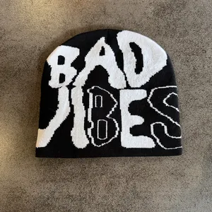 Close-up of black knit beanie with white Bad Vibes lettering in artistic gothic style