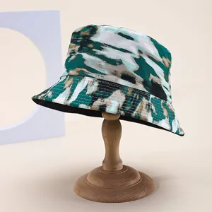 Green and brown tie-dye reversible cotton bucket hat on a wooden display stand