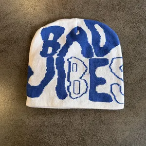 Detail view of white and blue knit beanie featuring Bad Vibes jacquard letter text