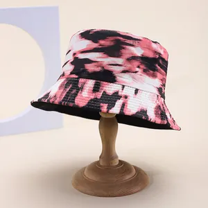 Tie-dye reversible bucket hat in pink and black on a wooden stand with studio lighting