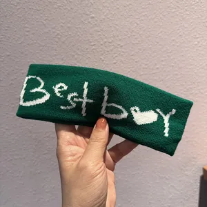 Dettaglio della fascia in maglia verde scuro con testo Best Boy bianco e motivo a cuore