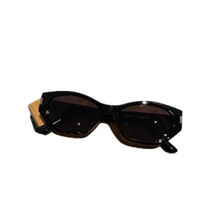 Vintage black cat-eye sunglasses with gray lenses and metallic hinge detail on wood base