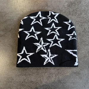 Detailopname van zwarte gebreide muts met witte sterrenpatroon en fijne jacquardtextuur