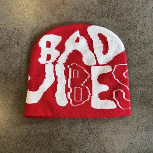 Close-up of red knit beanie showing detailed white BAD VIBES lettering texture