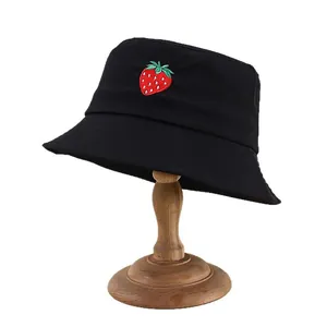 Women's black cotton bucket hat with strawberry embroidery on a wooden stand
