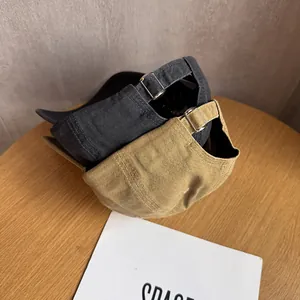 Classic baseball caps in black and khaki with adjustable metal buckles on a wood table