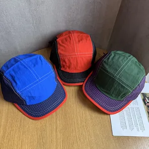 Three outdoor color-block quick-dry camper hats displayed on a rustic wooden table