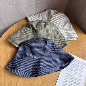 Navy blue, green, and beige plaid bucket hats with bow on wood table