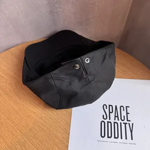 Béret rétro en coton noir avec bouton métallique sur table en bois et magazine