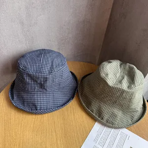 Detailed top view of navy and olive plaid bucket hats on a rustic wooden table surface