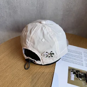 Detail view of beige ripstop baseball cap with adjustable drawstring and embroidery