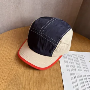 Close-up of a 5-panel outdoor cap with color-block navy and beige fabric on a wooden table