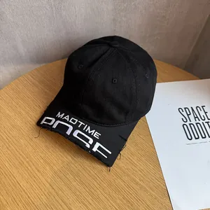 Detail of black cotton baseball cap with white embroidery and distressed frayed brim edges
