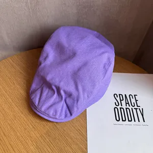Texture détaillée d'un béret en coton violet lavande posé sur une table en bois