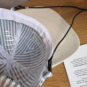 Close-up of baseball cap with striped lining and adjustable black windproof cord