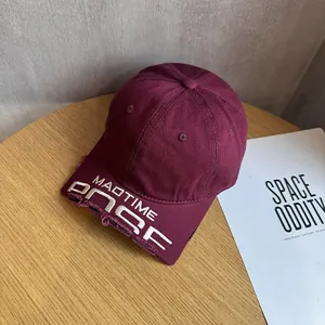 Close-up of distressed brim details and white embroidery on a burgundy baseball cap