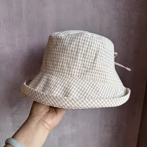Detail view of beige plaid bucket hat fabric and brown checked pattern with back tie